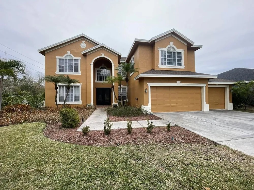 Two-story tan stucco home with fresh white trim and new landscaping