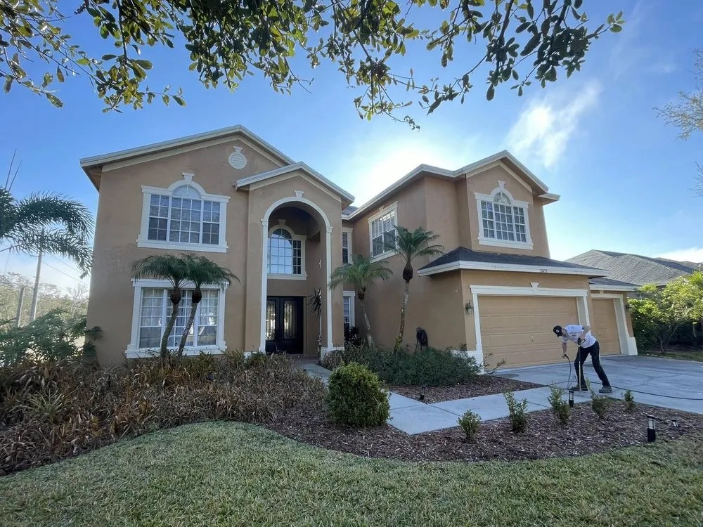 Stucco home after painting with a crew member in the driveway